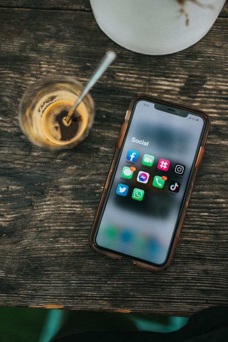 Smartphone displaying social media apps next to a cup of coffee