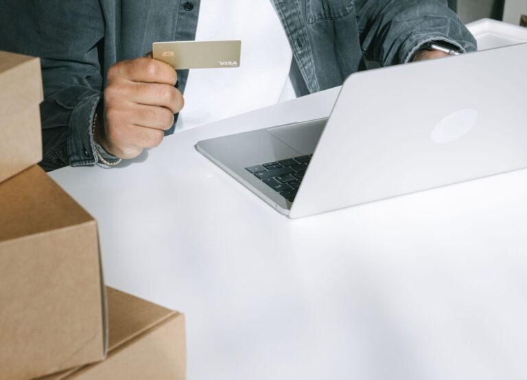 Person paying by card on a laptop surrounded by shipping boxes
